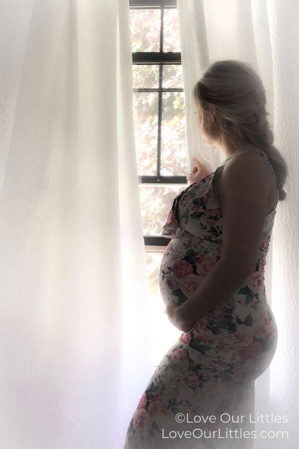 Pregnant woman taking a diy silhouette maternity photo in front of a window.